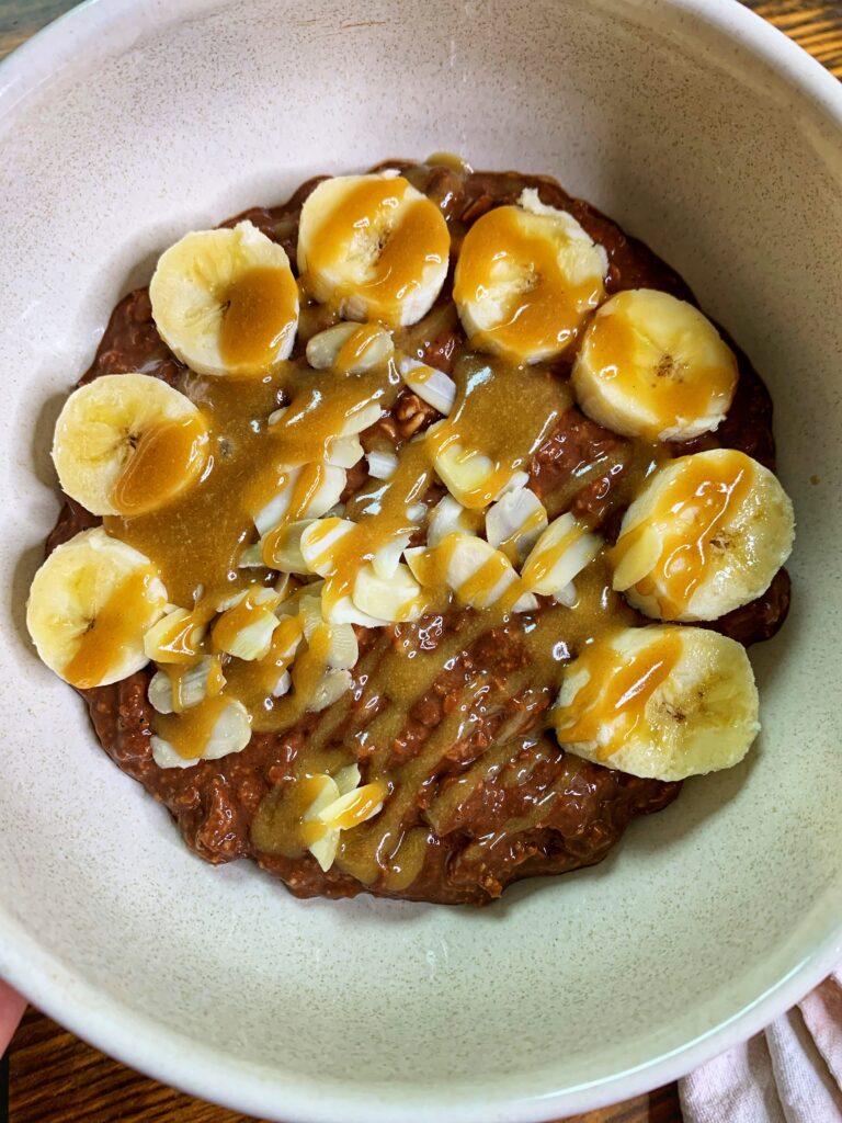 Brownie batter overnight oats, served with banana and tahini maple caramel